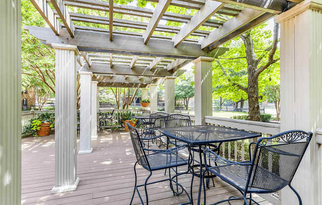 Clubhouse exterior patio with pergola, wrought iron tables and chairs with native landscape