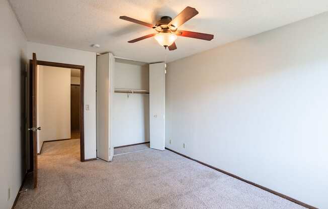 the living room of an empty apartment with a ceiling fan. Eagan, MN Glen Pond Apartments