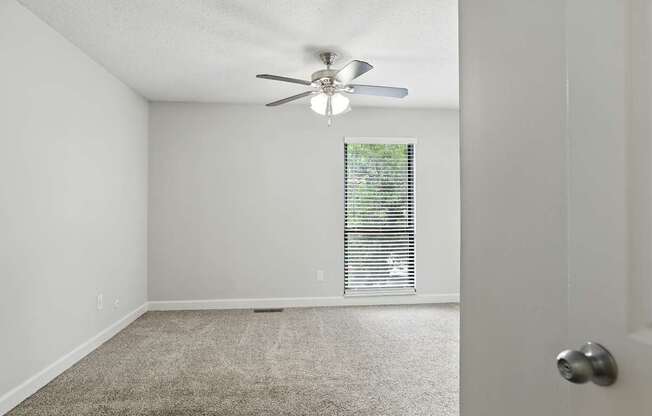A room with a ceiling fan and carpeted floor.