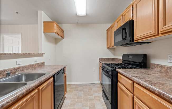 a kitchen with granite counter tops and a black stove and microwave at Dronfield Astoria, Sylmar, CA