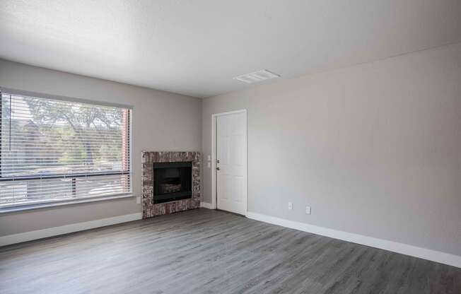 an empty living room with a fireplace and a window