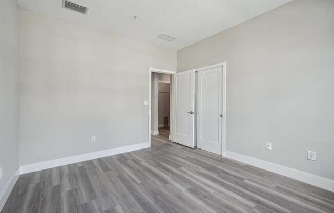 an empty living room with wood floors and white walls
