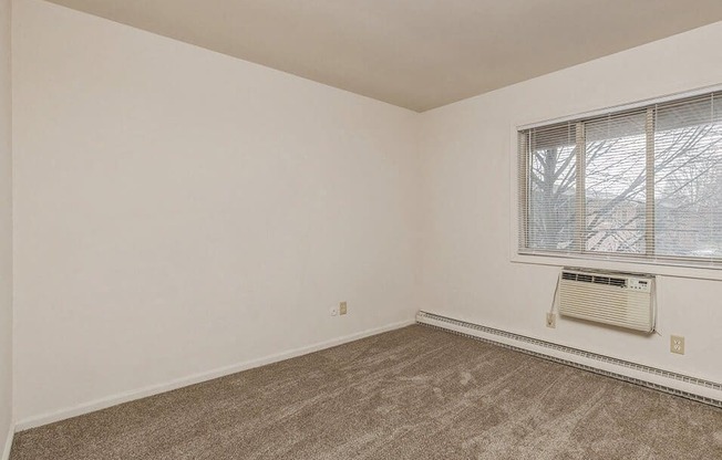 an empty room with a window and a radiator