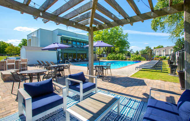 A patio with blue cushions and a pool in the background.
