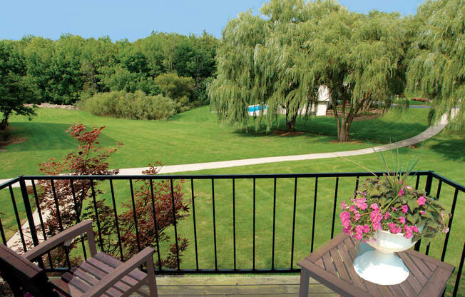 A balcony with a table and chairs overlooking a green lawn.