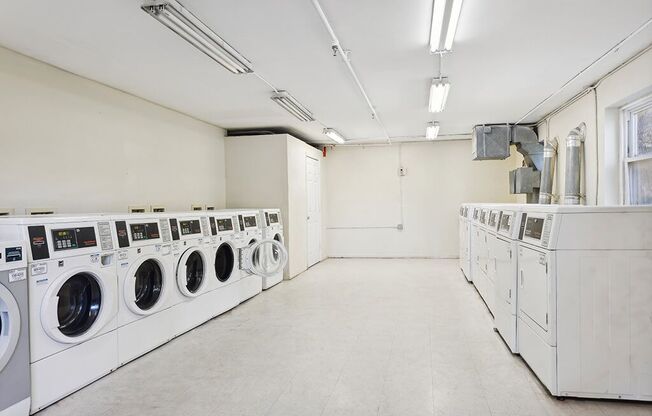 a laundry room with lots of washing machines and dryers