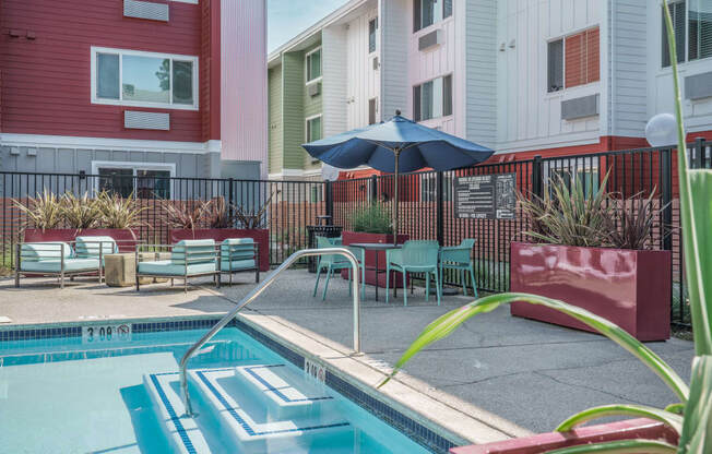 our apartments have a pool and a patio with chairs and an umbrella