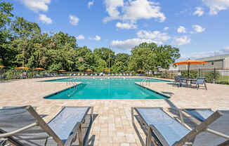 A pool surrounded by lounge chairs and umbrellas at Staples Mill Townhomes Apartments, Richmond, VA, 23228