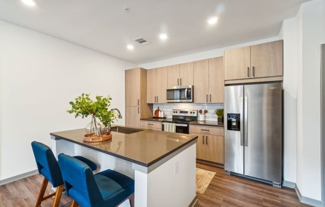 a kitchen with a large island and a stainless steel refrigerator