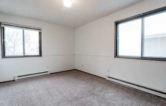 A room with a carpeted floor and two windows. at Bristol Ridge, Urbandale