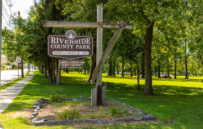 A sign for Riverside County Park is displayed in front of a wooded area at Vermella Lyndhurst apartments, Lyndhurst