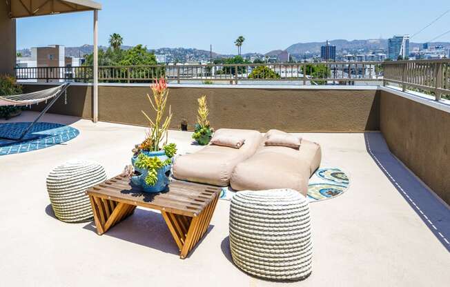 a rooftop terrace with couches and tables and a view of the city