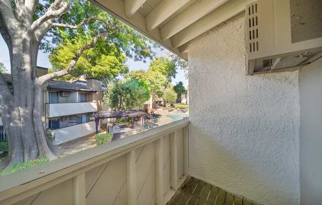 a balcony with a view of a tree and some buildings