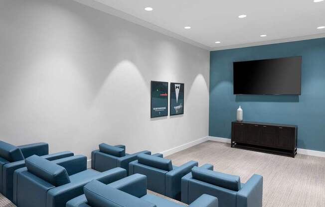 A room with blue couches and a flat screen TV mounted on the wall.