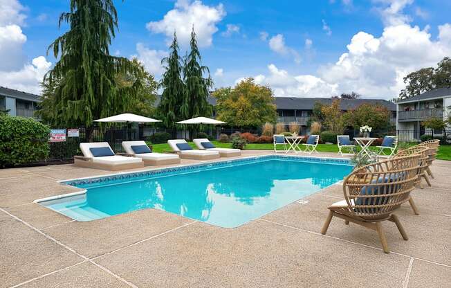 A pool surrounded by chairs and trees.