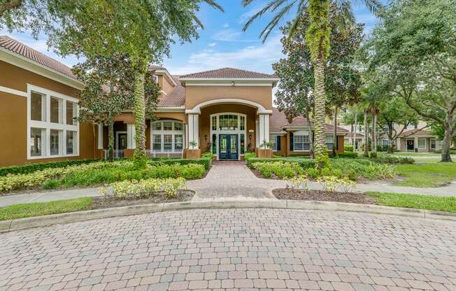 A brick pathway leads to a building entrance surrounded by greenery.