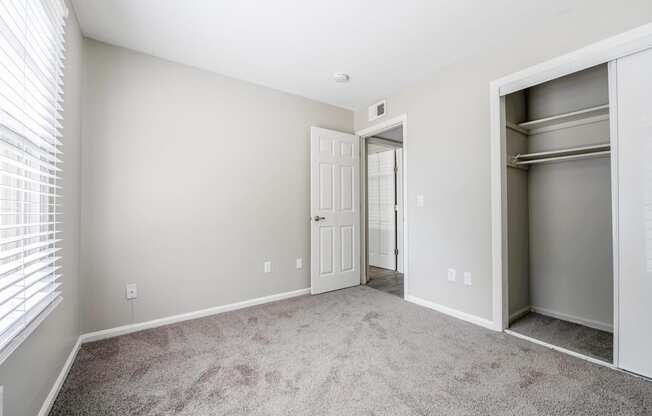 A room with a white door and a grey carpet.