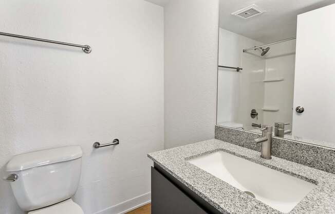 A bathroom with a toilet, sink, and mirror.