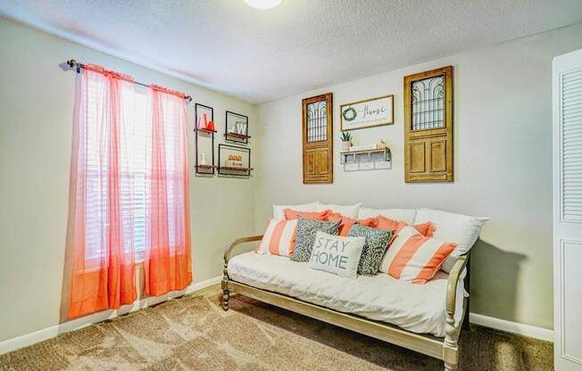 A bedroom with a bed and a window with orange curtains.