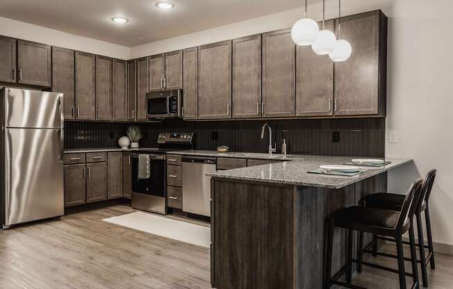 A modern kitchen with dark wood cabinets and stainless steel appliances.