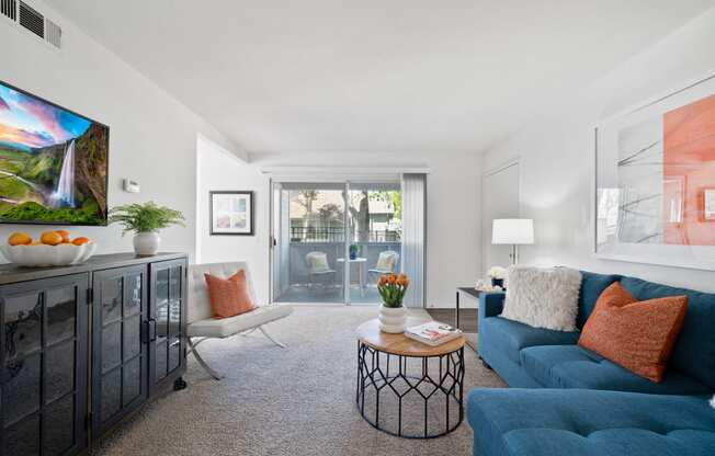 a living room with a blue couch and a sliding glass door