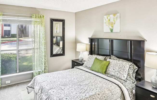 Model apartment bedroom with a bed and a large window at Hunters Chase in Austin, TX