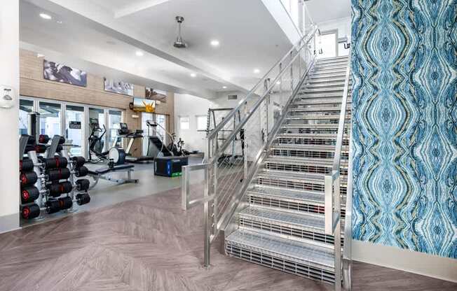 A staircase with a metal railing and a blue patterned wallpaper on the wall.