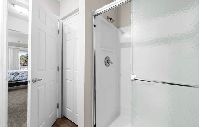 A white bathroom with a glass shower door.