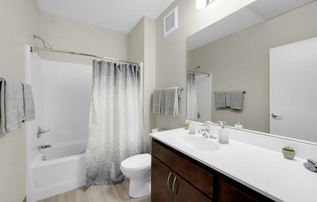 a bathroom with a white sink and toilet next to a white bathtub with a shower curtain