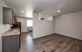A kitchen with dark wood floors and a black refrigerator.