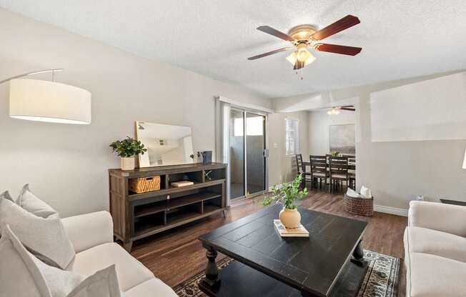 A living room with a white couch, a wooden coffee table, and a ceiling fan.