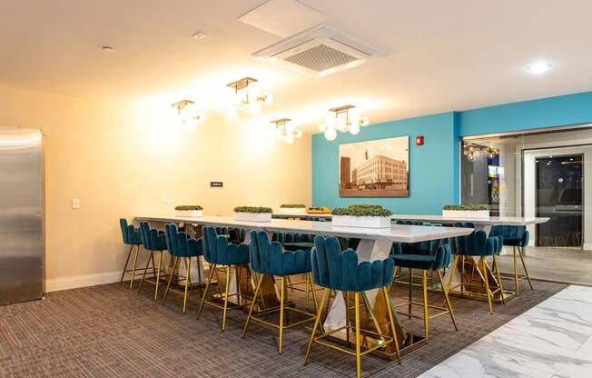 a long table with blue chairs in a room with a refrigerator