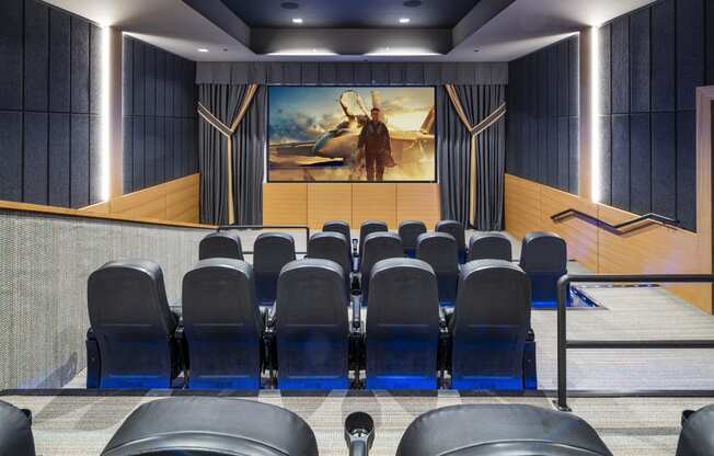 a large auditorium with blue chairs and a painting on the wall