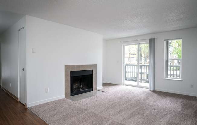 an empty living room with a fireplace and a patio door