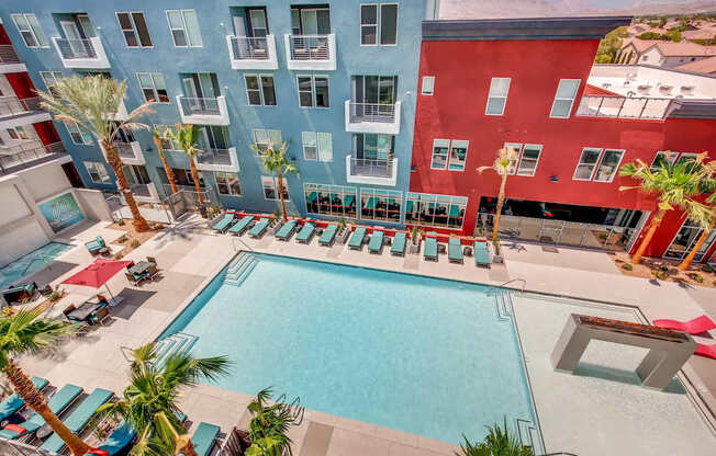 A swimming pool surrounded by palm trees and lounge chairs.