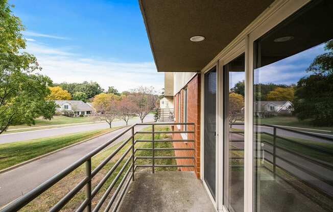 a balcony with a view of a street and some trees