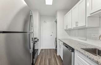 A kitchen with a stainless steel refrigerator and a granite countertop.