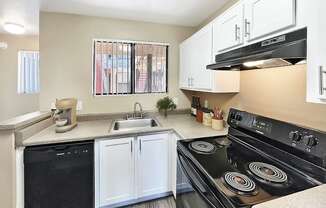 A kitchen with black appliances and white cabinets.