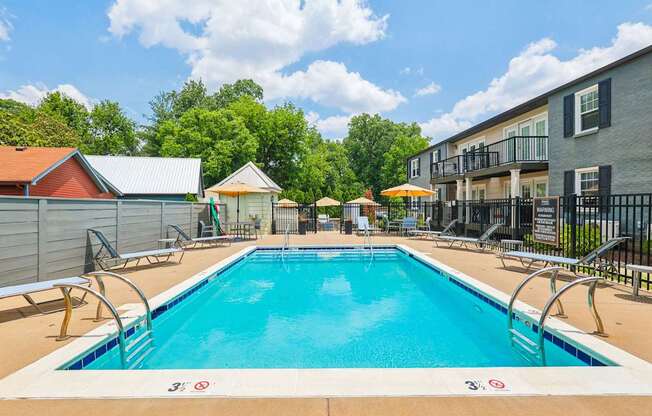 A swimming pool surrounded by a metal fence and a building in the background.