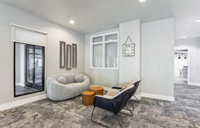 a lounge area with a white couch and chairs and a large window