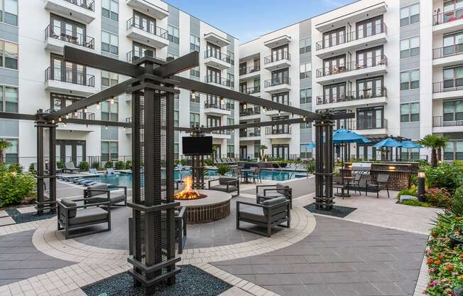 an outdoor lounge area with a firepit and lounge chairs next to an apartment building