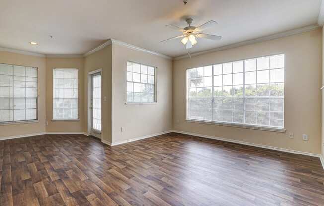 Bright living and dining rooms with large windows and wood floring at Turnberry Isle Apartments in Dallas, TX.