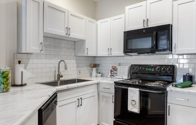 a kitchen with white cabinets and black appliances