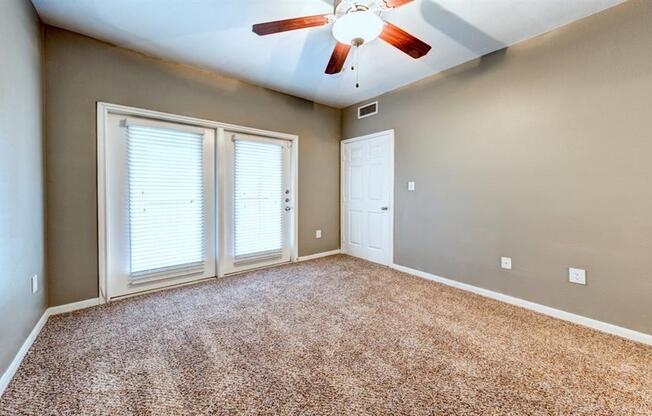 Bedroom with balcony doors and ceiling fan