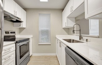 a kitchen with white cabinets and stainless steel appliances at 2000 Lake Washington Apartments, Renton