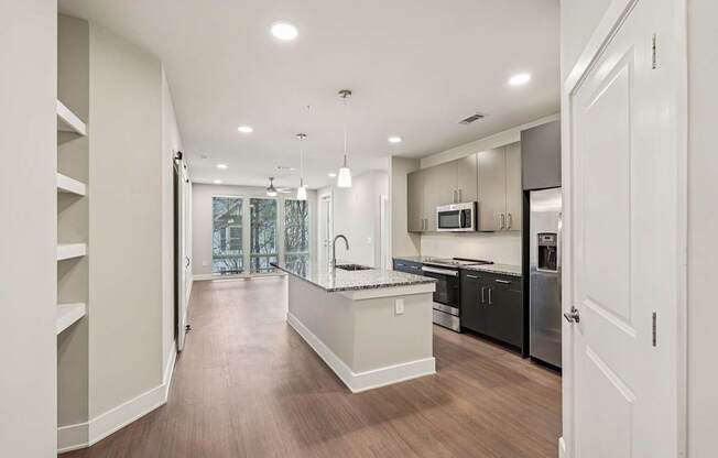 A modern kitchen with a large island and stainless steel appliances, plus floor to ceiling windows .
