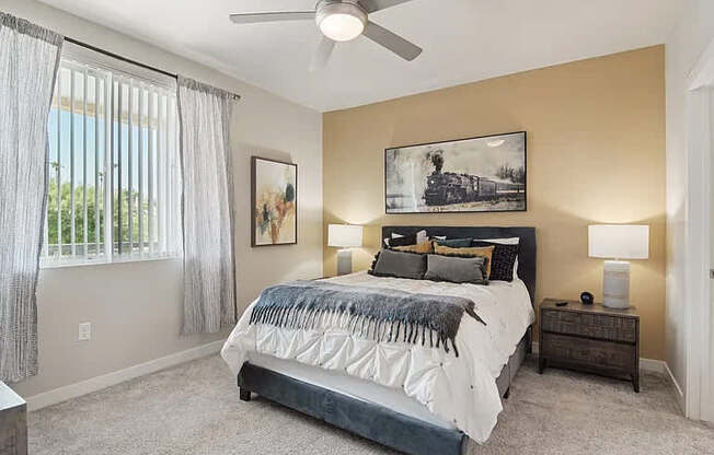 A bedroom with a large bed, a ceiling fan, and a window with curtains.