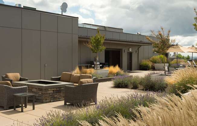 A modern outdoor seating area with a stone wall and wicker furniture.