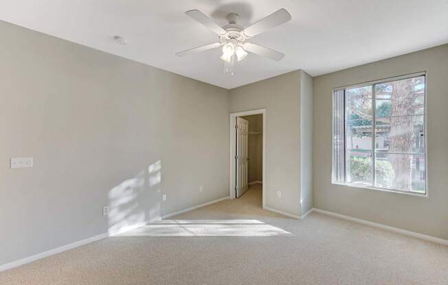 A room with a ceiling fan and a window.