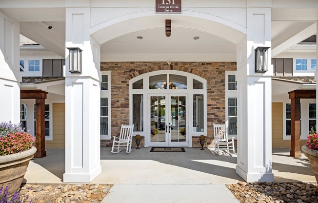 the front entrance of a building with white columns and a large archway with chairs